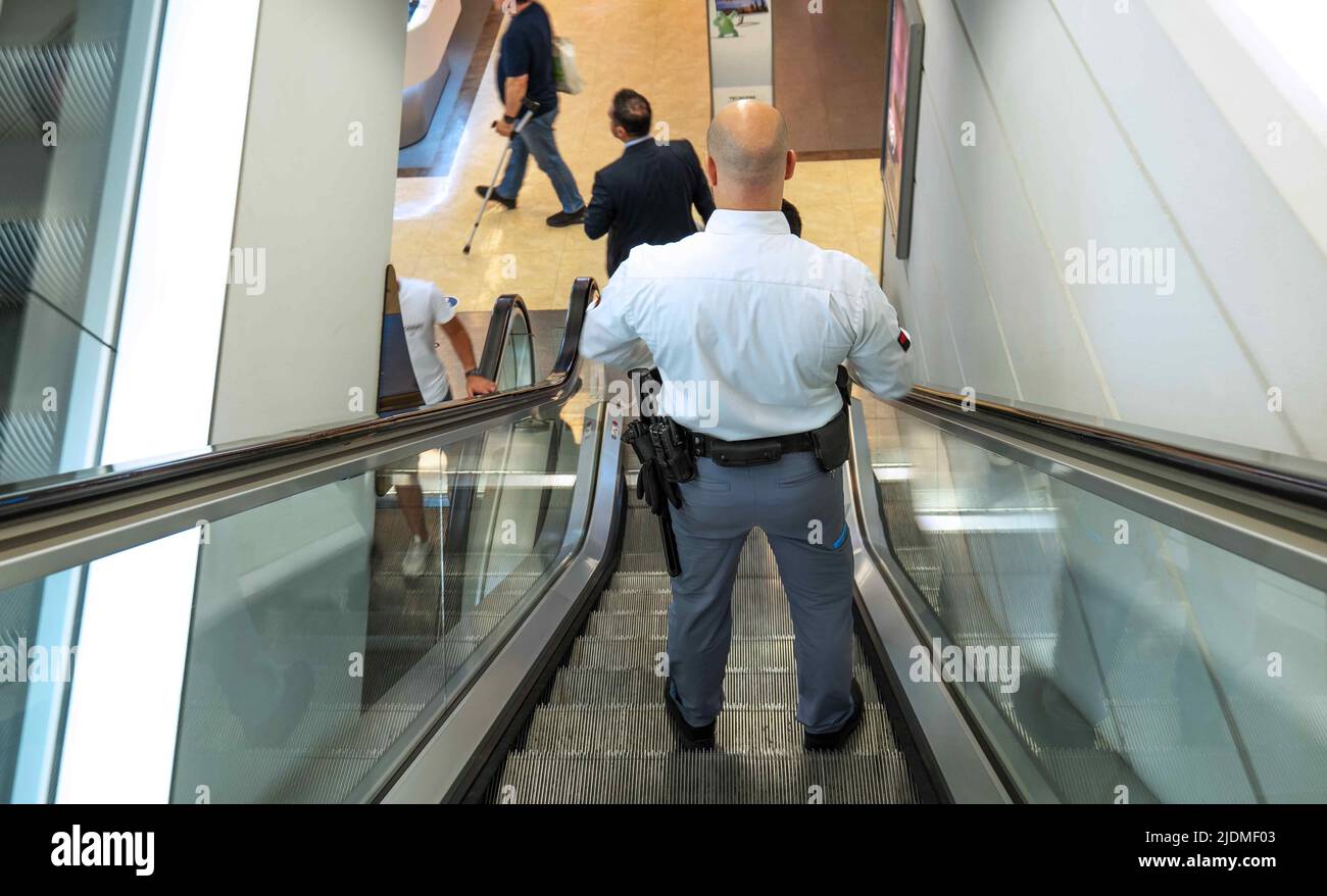 Maskuliner Wachmann steht auf der Rolltreppe im Kaufhaus. Stockfoto Maskuliner Wachmann steht auf der Rolltreppe im Kaufhaus. Stockfoto
