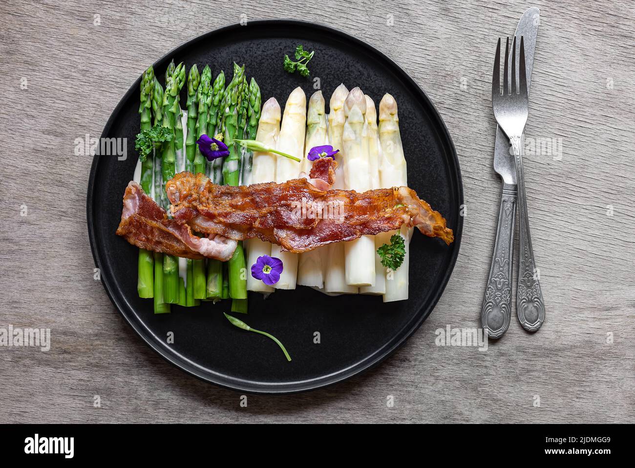 Grüner und weißer Spargel mit gebratenem Speck. Stockfoto