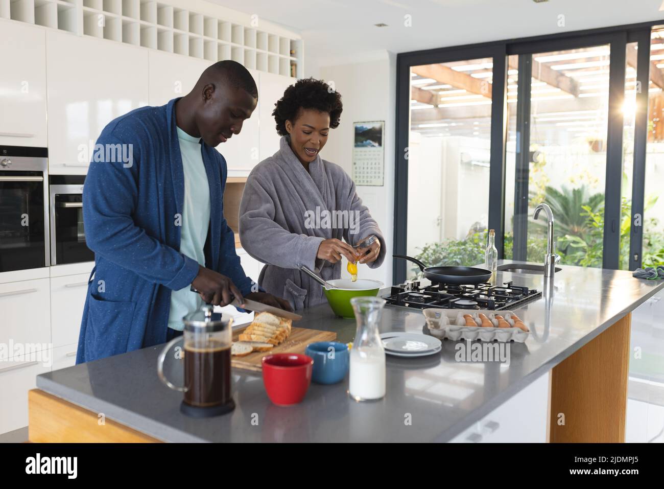 afroamerikanisches Ehepaar mit mittleren Erwachsenen, das in Bademänteln in der Küche frühstücken kann Stockfoto