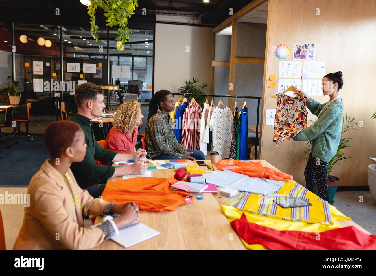 Biracial weibliche Mode-Designerin zeigt Kleidungsstücke zu multirassischen Kollegen in der Sitzung im Büro Stockfoto