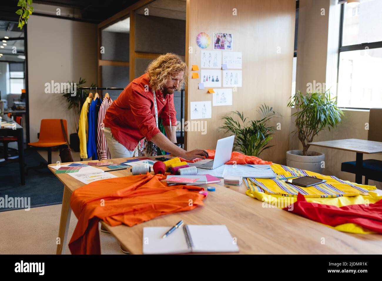 Kaukasischer Modedesigner, der im Studiobüro einen Laptop am Schreibtisch verwendet Stockfoto