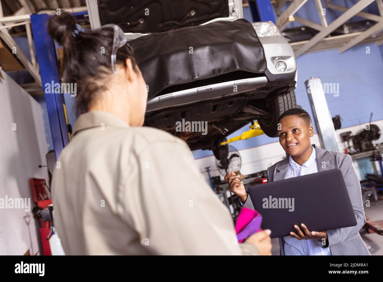 afroamerikanische Ingenieurin für mittlere Erwachsene, die mit einem Laptop arbeitet, während sie mit einer asiatischen Kollegin zusammenarbeitet Stockfoto