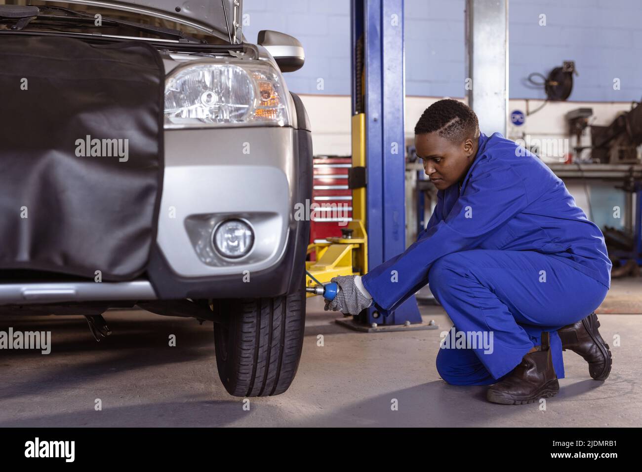 afroamerikanische mittlere Erwachsene weibliche Mechanikerin mit Arbeitswerkzeug während der Reparatur Auto in der Werkstatt Stockfoto