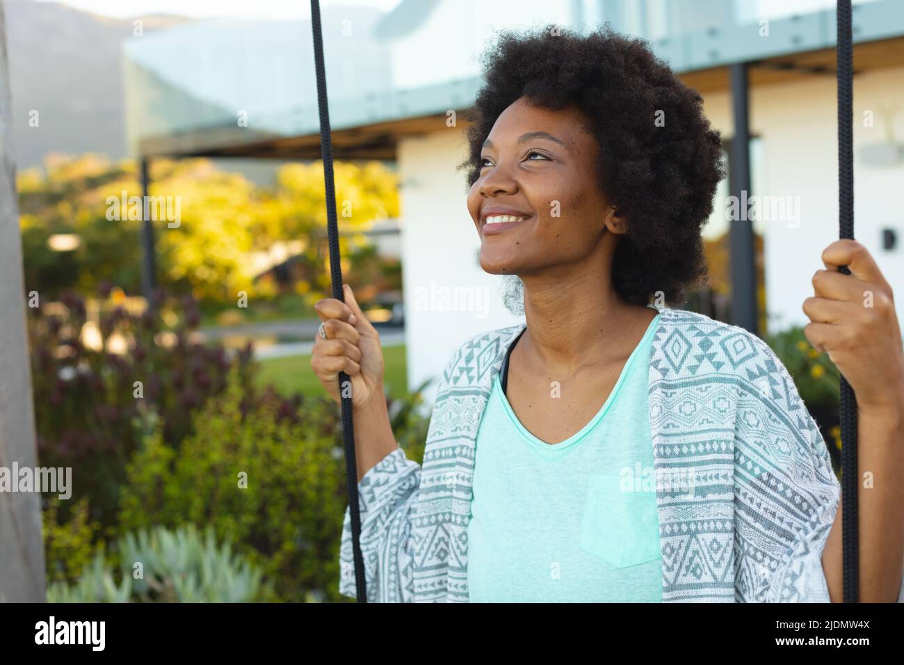 Lächelnde junge afro afroamerikanische Frau, die vor dem Haus wegschaut Stockfoto