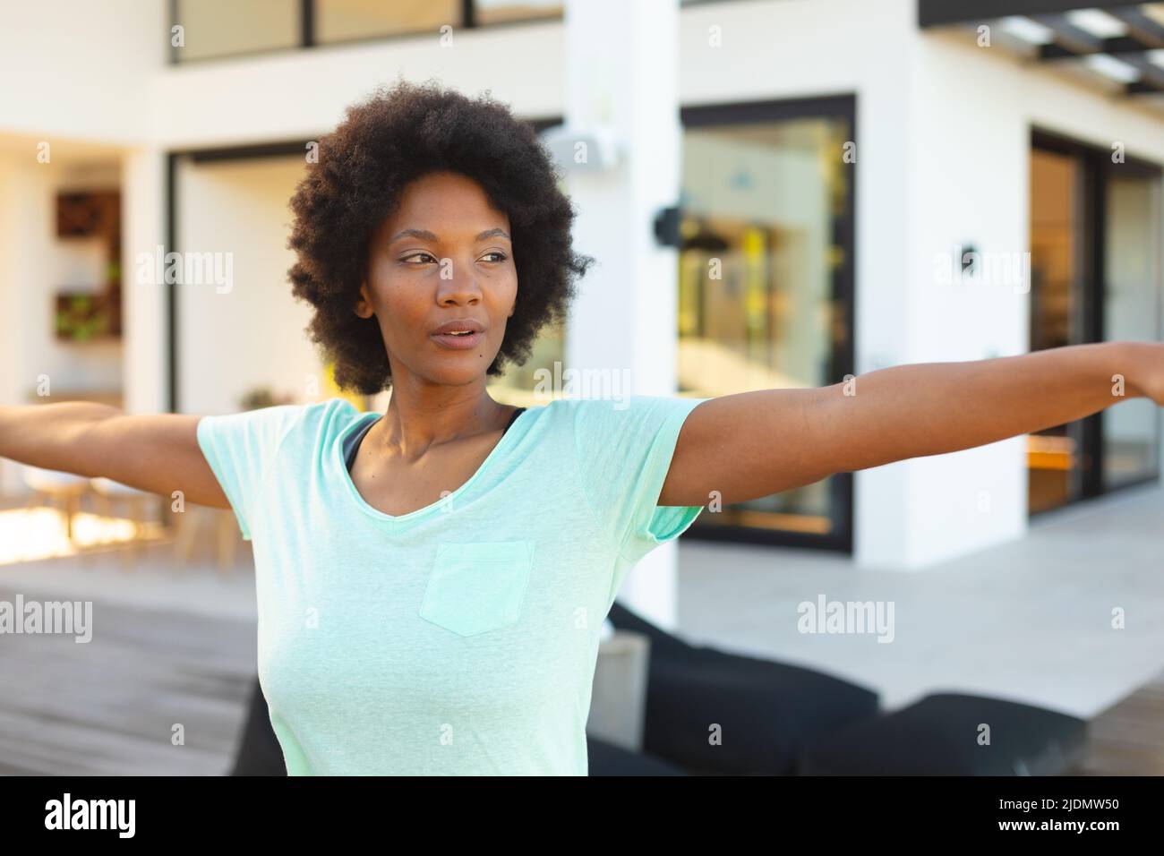 Selbstbewusste junge afro afroamerikanische Frau mit ausgestreckten Armen, die im Hinterhof trainieren Stockfoto