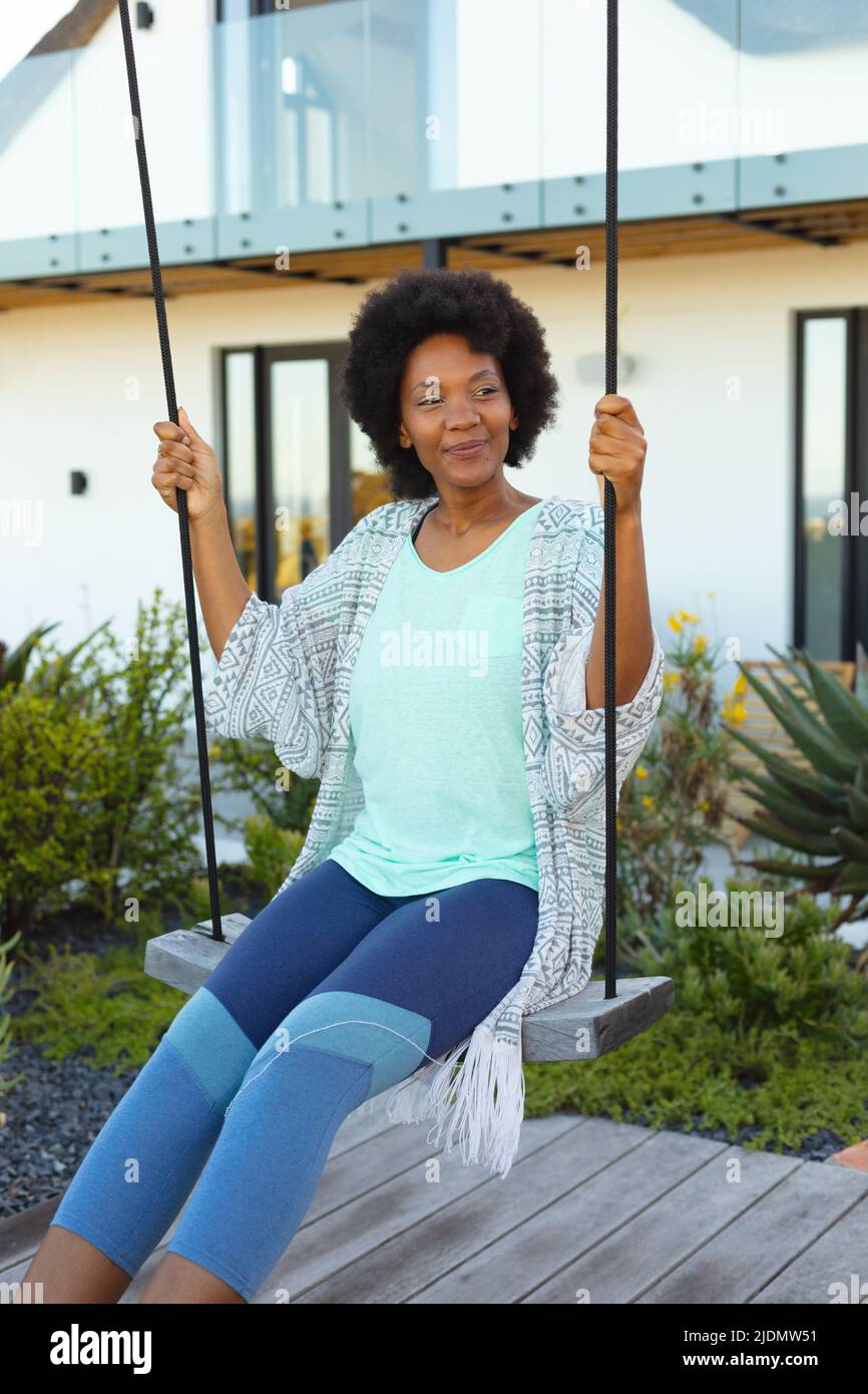 Junge afro afroamerikanische Frau schwingt auf Schaukel im Hinterhof Stockfoto