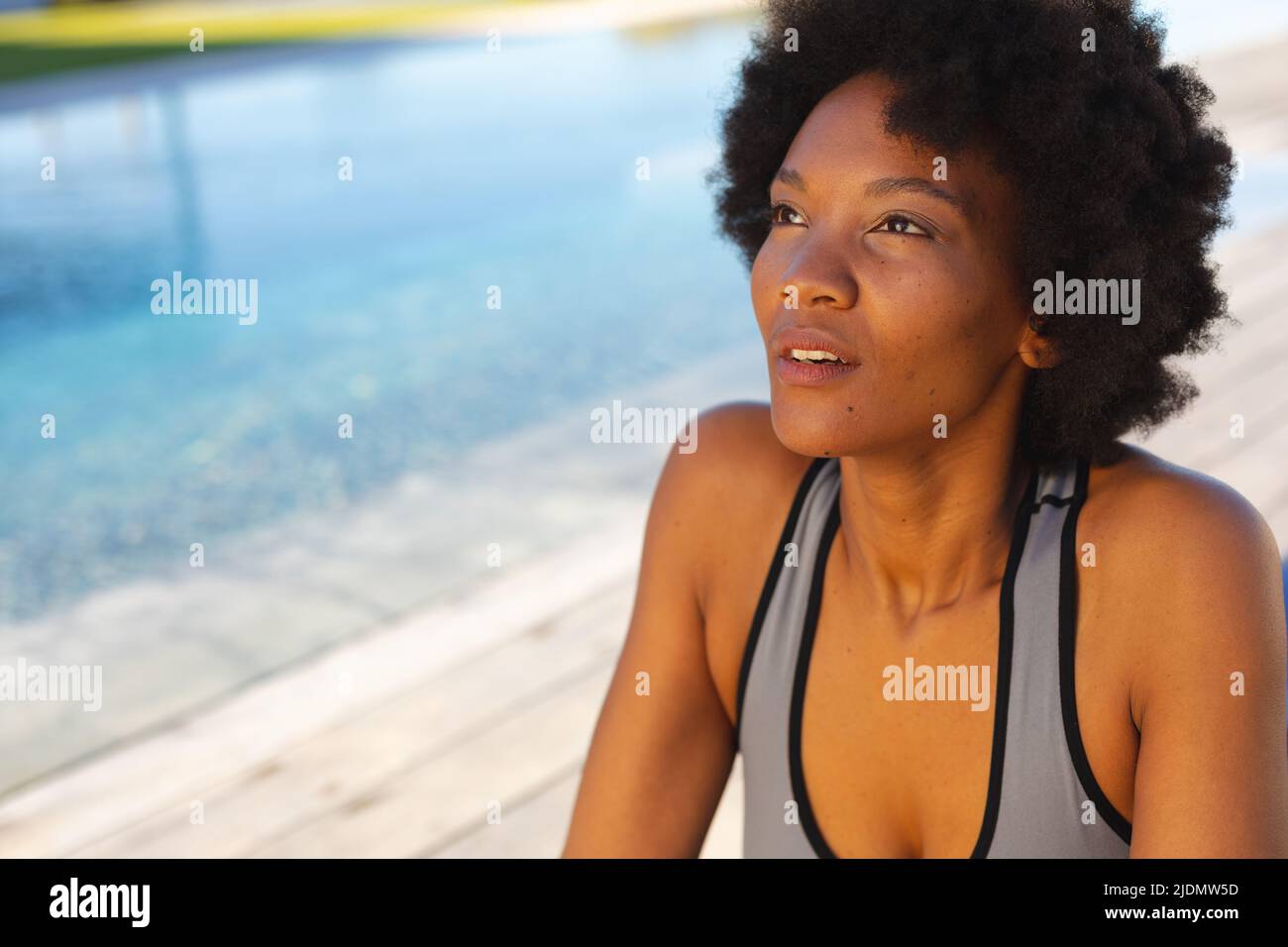 Afro-afroamerikanische junge Frau schaut weg, während sie am Pool trainiert Stockfoto