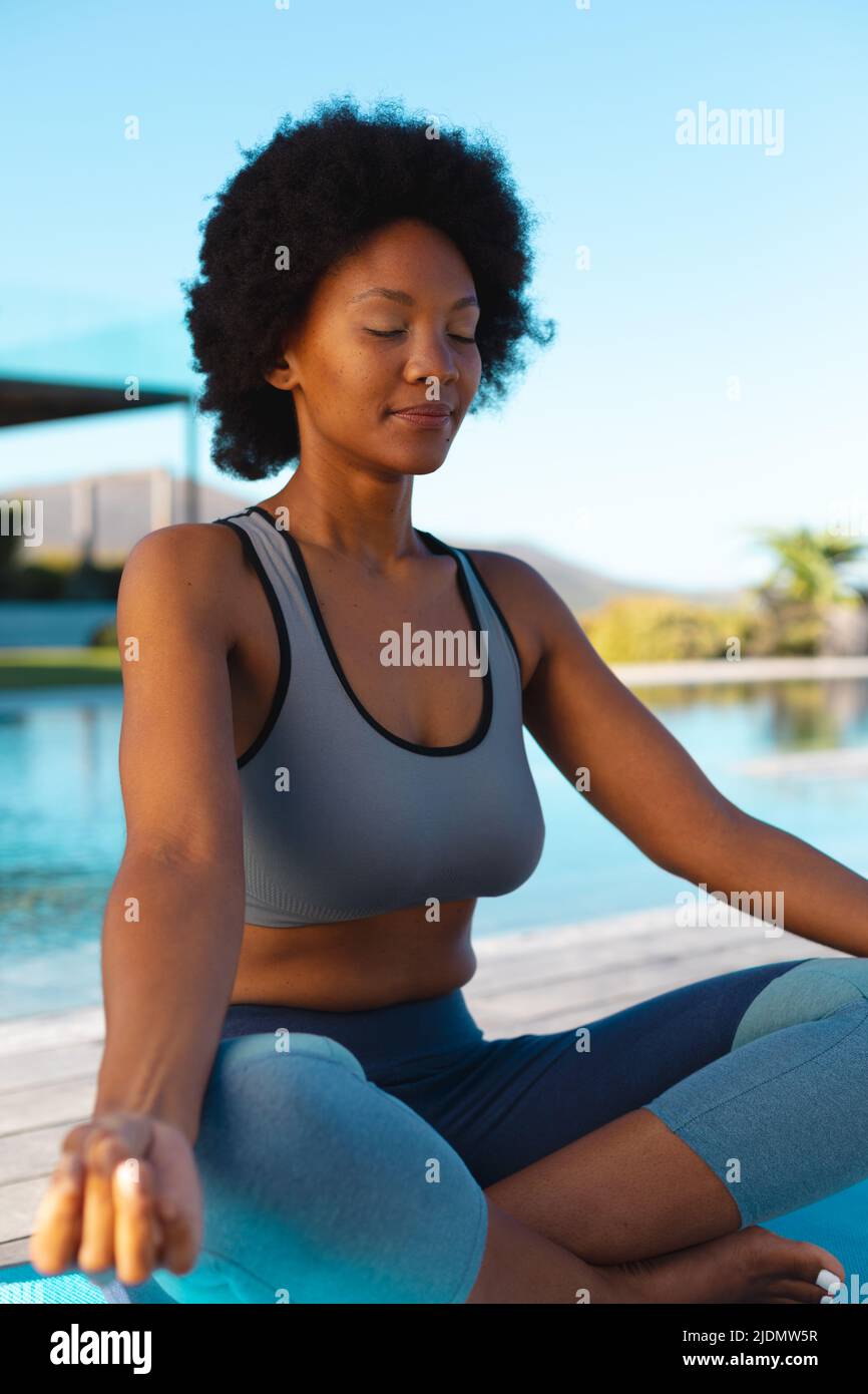 Junge afro afroamerikanische Frau meditiert am Pool, Kopierraum Stockfoto