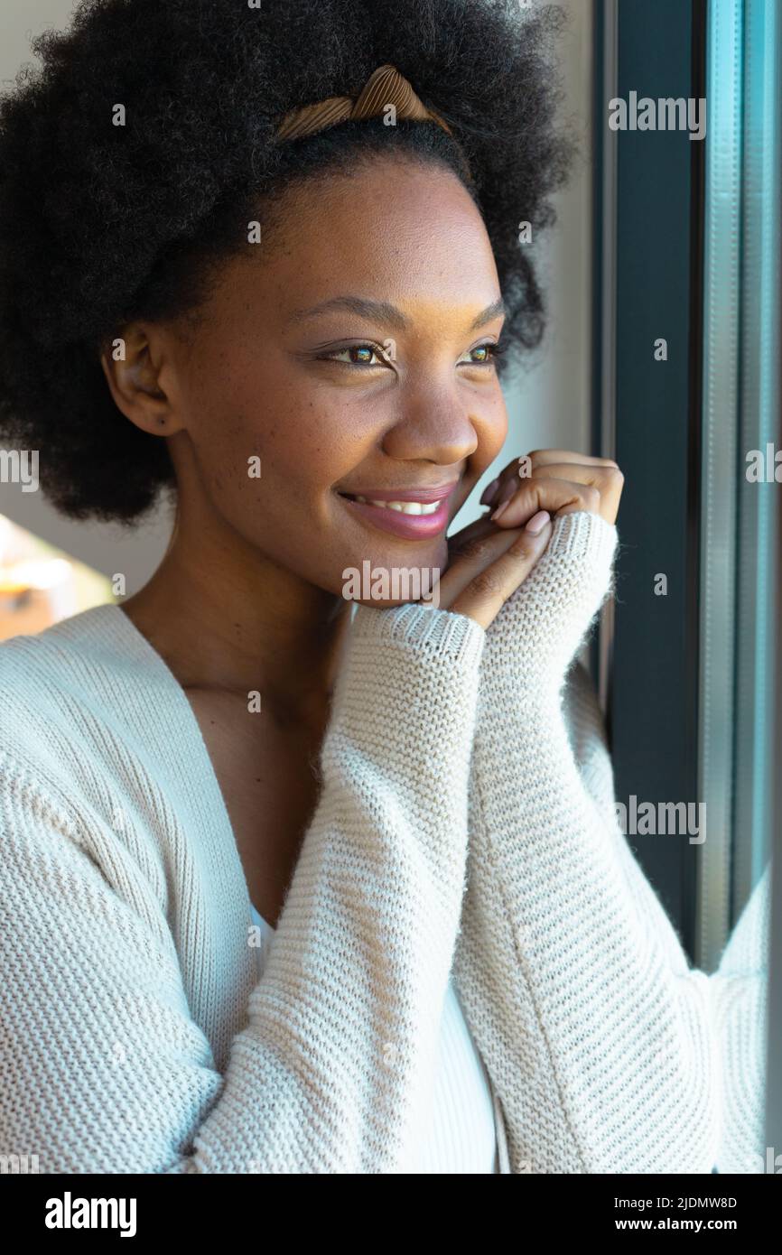Lächelnde afro afroamerikanische junge Frau, die zu Hause wegschaut Stockfoto