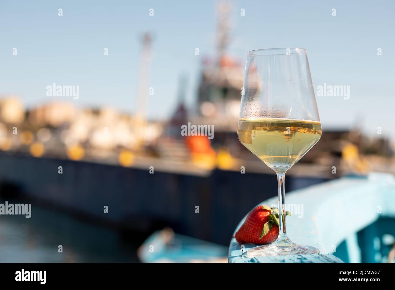 Komposition aus Glas mit Weißwein und Erdbeere an Bord eines blauen Holzbootes an sonnigen Tagen. Weichfokus. Stockfoto