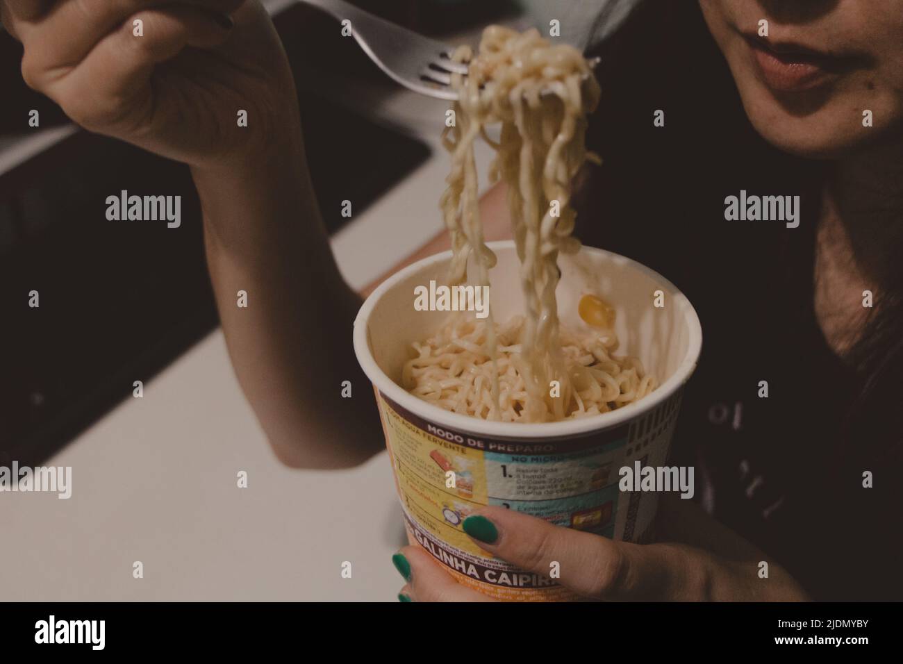 Junge Frau, die Pasta in einer Tasse isst Stockfoto