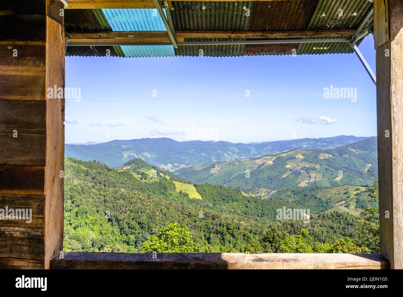 Schöner Doi Sakad Berg mit Wiese und Wald durch das Holzfenster im lokalen Haus, das in PUA, Nan, Thailand, liegt Stockfoto