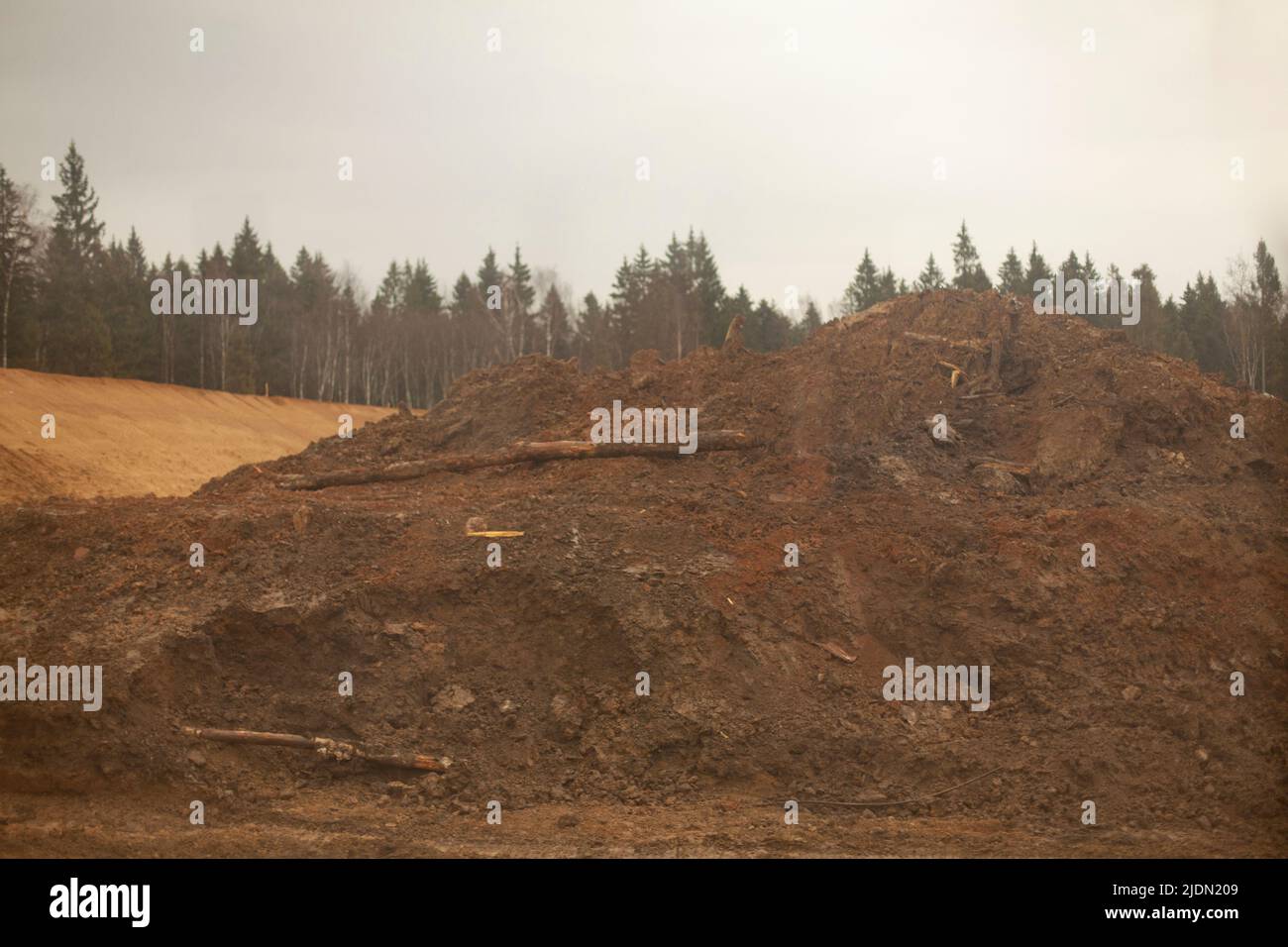 Berg aus Sand auf der Linie. Ausgegrabene Erde. Beginn des Baus der Straßenkreuzung. Baumaterial... Hügel für Fundament schaffen. Stockfoto