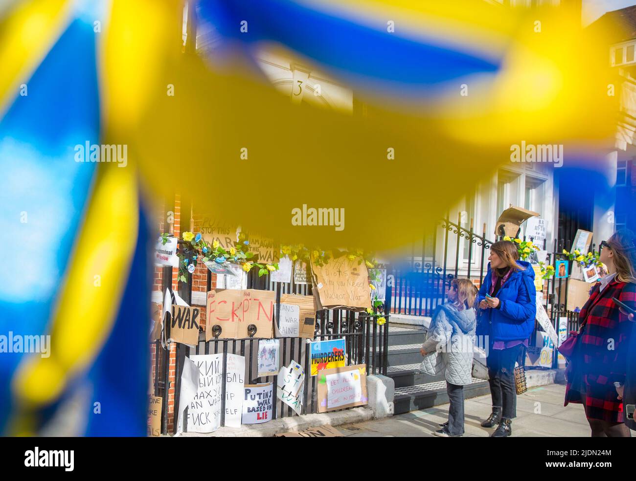 Blaue und gelbe Bänder werden vom Wind geblasen, während Botschaften gegen die russische Invasion in der Ukraine in der Nähe der russischen Botschaft in London hinterlassen werden. Stockfoto