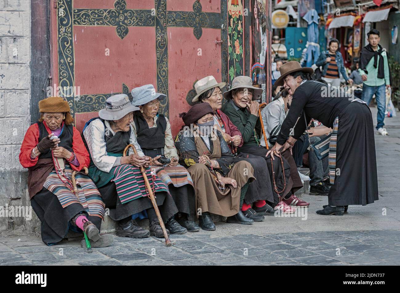 LHASA, TIBET, CHINA - AUGUST 18 2018: Alte tibeter in traditioneller Kleidung sitzen auf einer Bank in der Nähe des Jokhang-Tempels Stockfoto