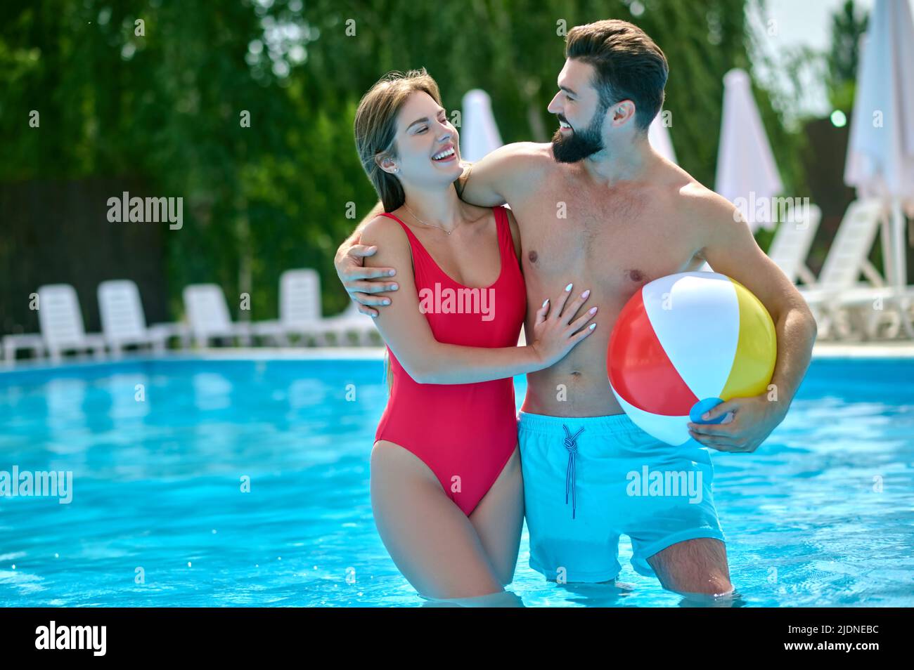 Romantischer Mann umarmt seine weibliche Gefährtin im Schwimmbad Stockfoto