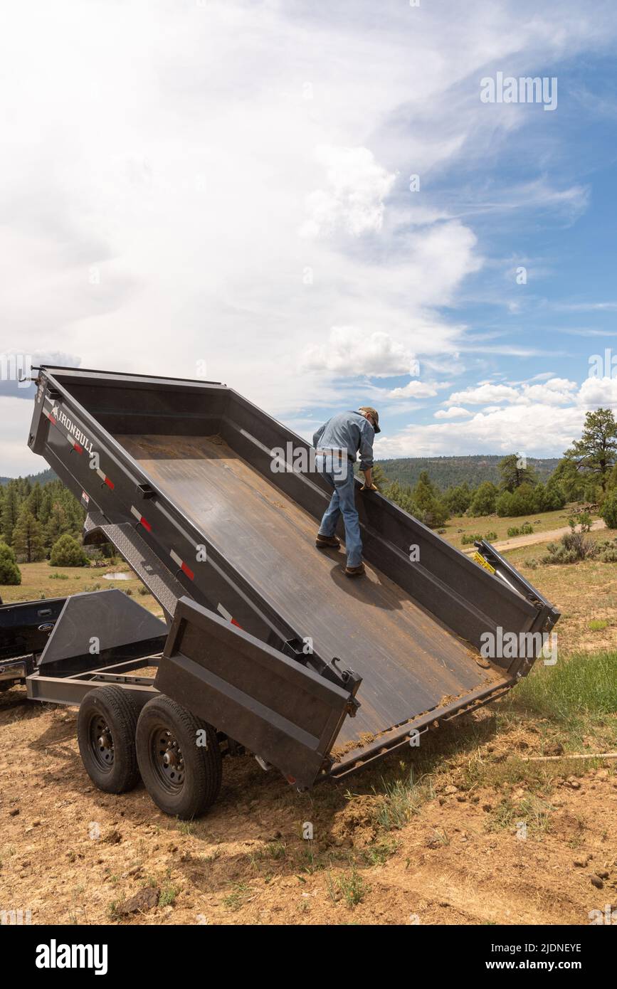 Ein Arbeiter steht auf einer Ranch im Norden von New Mexico auf dem Bett eines Iron Bull-Muldenkipper mit hydraulischem Aufzug. Stockfoto