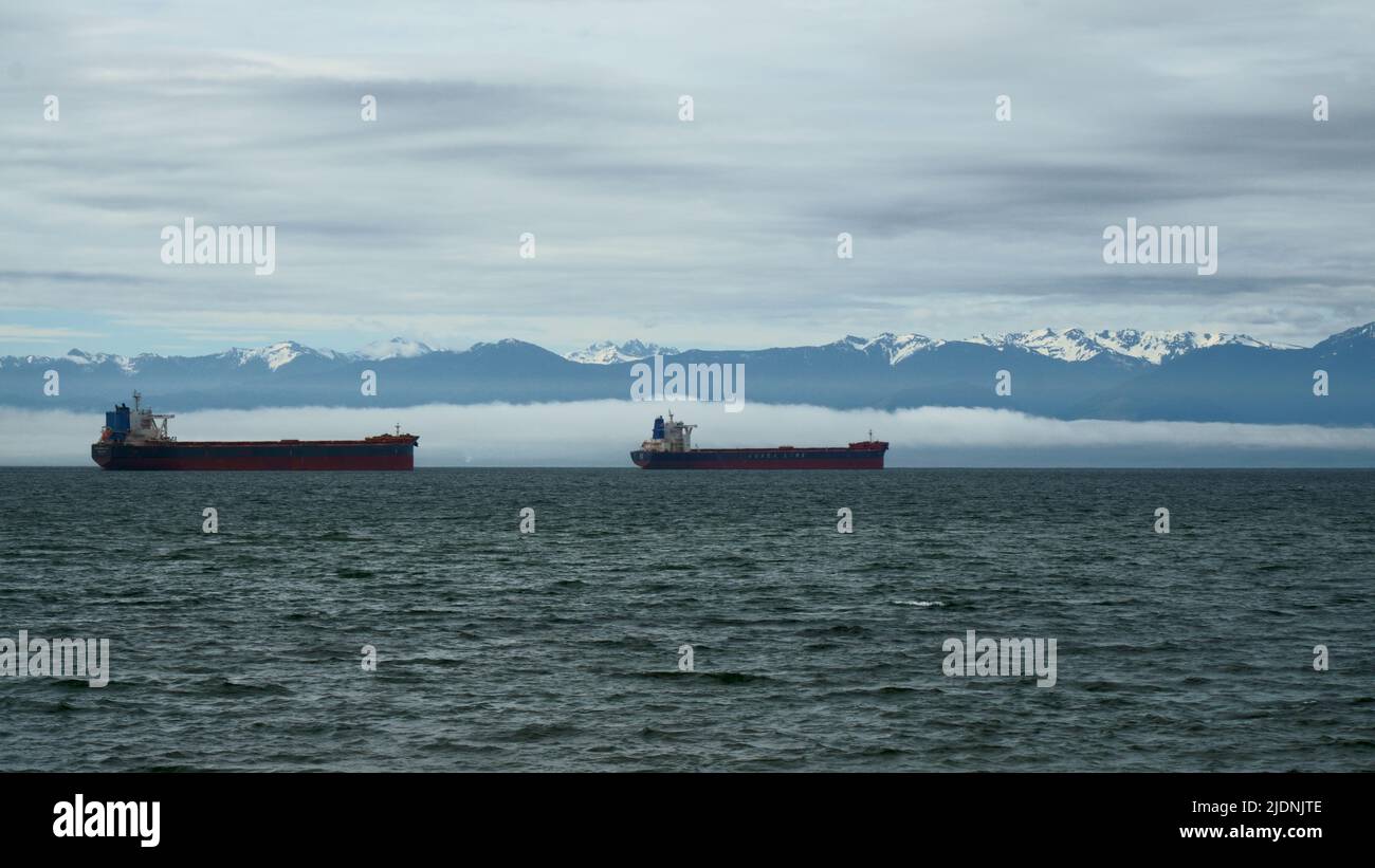 Handelsschiffe vor Anker. Berge im Hintergrund. Stockfoto