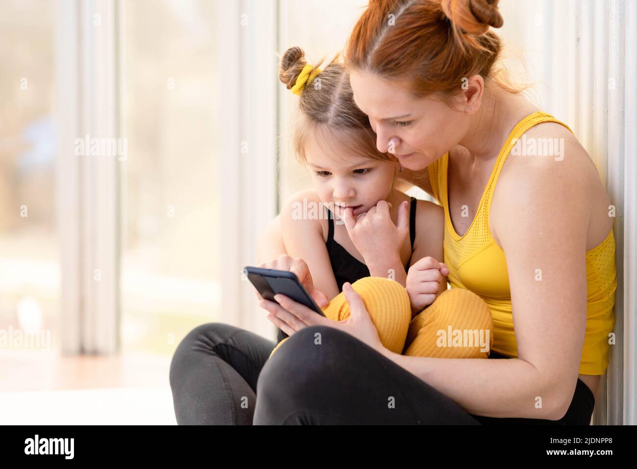 Junge, fick Mutter, die liebevolle Zeit mit ihrer Tochter, Blick auf ein Telefon zusammen Stockfoto