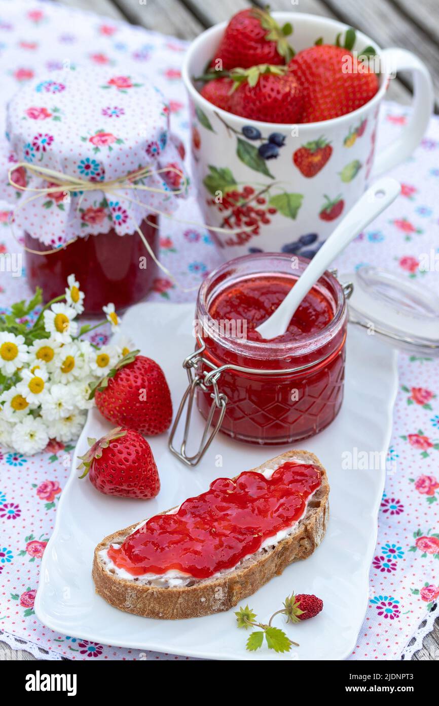 Erdbeermarmelade auf einem Stück Brot und im Glas Stockfoto