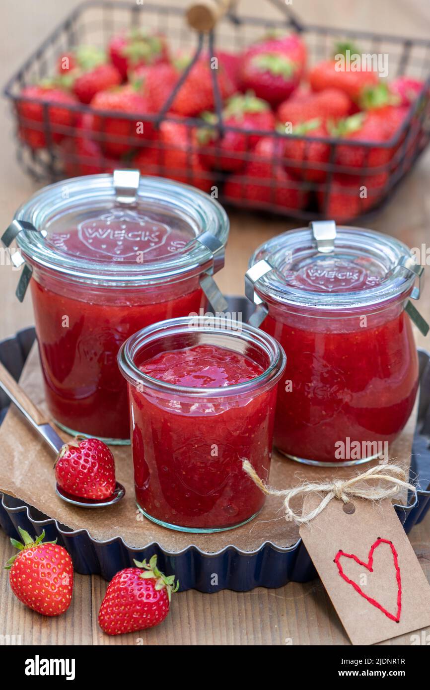 Erdbeermarmelade in Gläsern und frische Erdbeeren im Korb Stockfoto
