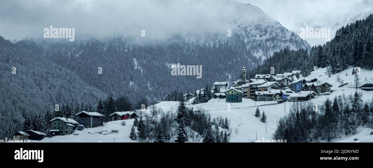 Blick auf ein schneebedecktes Dorf, typisch für die Ares der italienischen Alpen an der Grenze zur Schweiz. Stockfoto