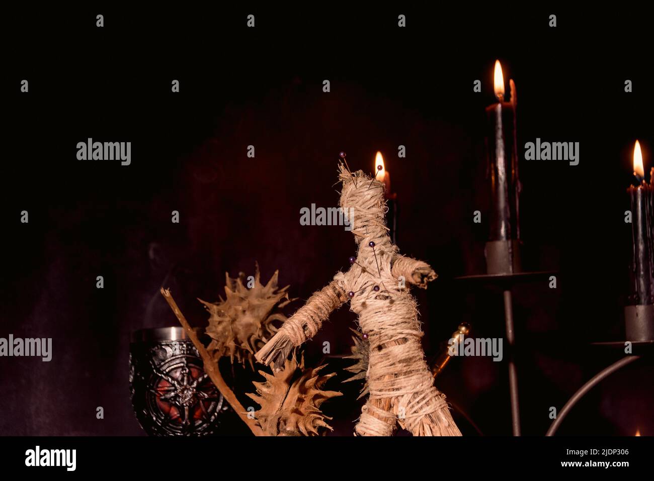 Gruselige Voodoo Puppe mit schwarzen Kerzen. Mystischer Hintergrund mit rituellen esoterischen Objekten, okkulten und halloween-Konzept. Stockfoto