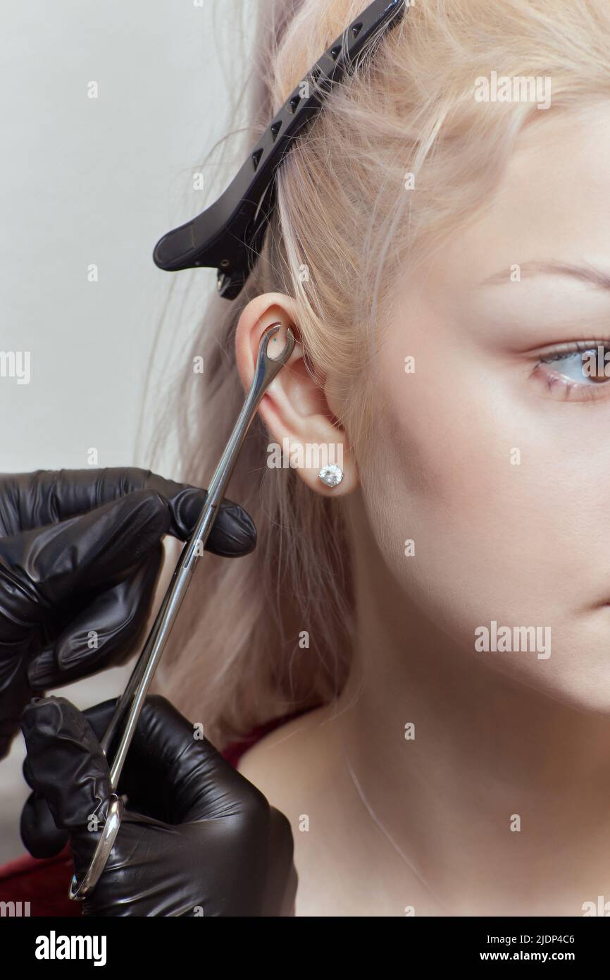 piercings auf dem Ohr. Muschel- und Helix-Piercings aus der Nähe. Professionell halten das Juwel Stockfoto