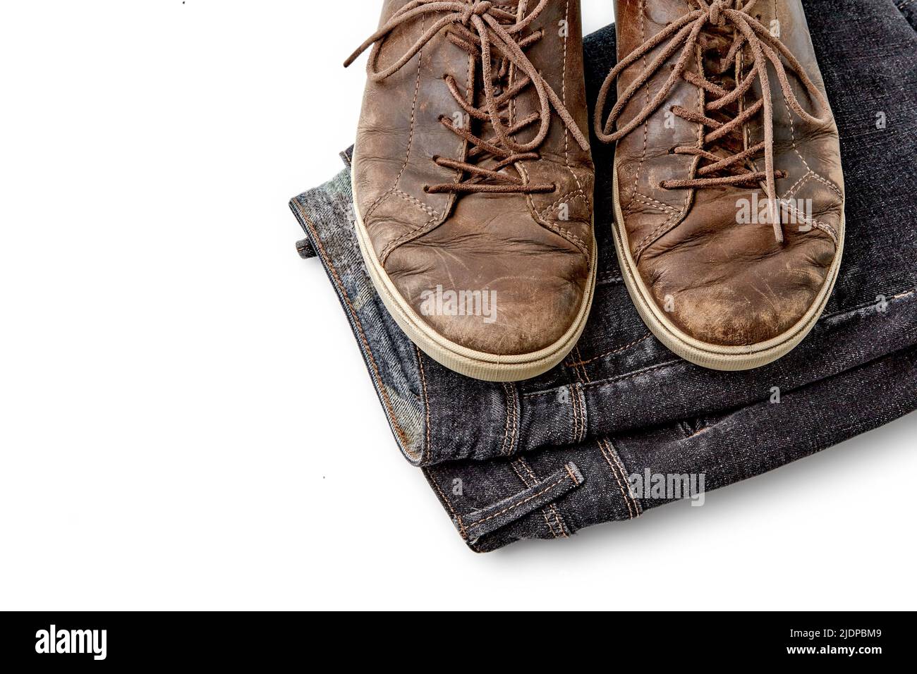 Stilvoll verzweifelte Vintage braune Lederschuhe und schwarze Jeans auf weißem Hintergrund isoliert. Lifestyle und Mode. Obere Aussicht mit Kopierbereich Stockfoto