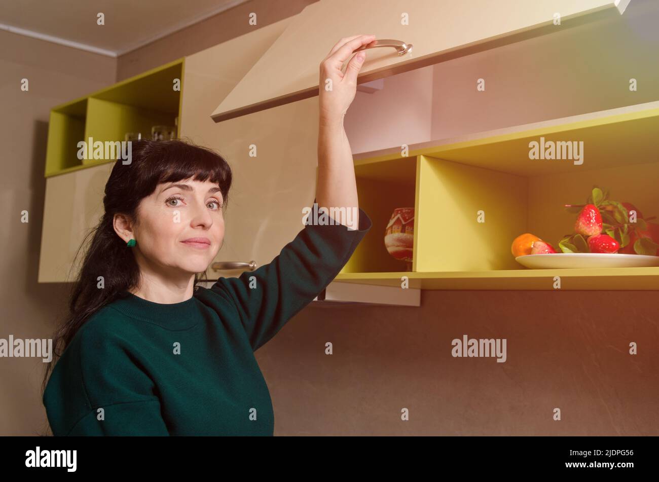 Attraktive Frau hebt Schranktür mit Silent Mechanismus Stockfoto