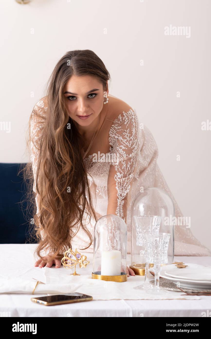 Die Braut kriecht wie eine Katze auf den Tisch. Hochwertige Fotos Stockfoto