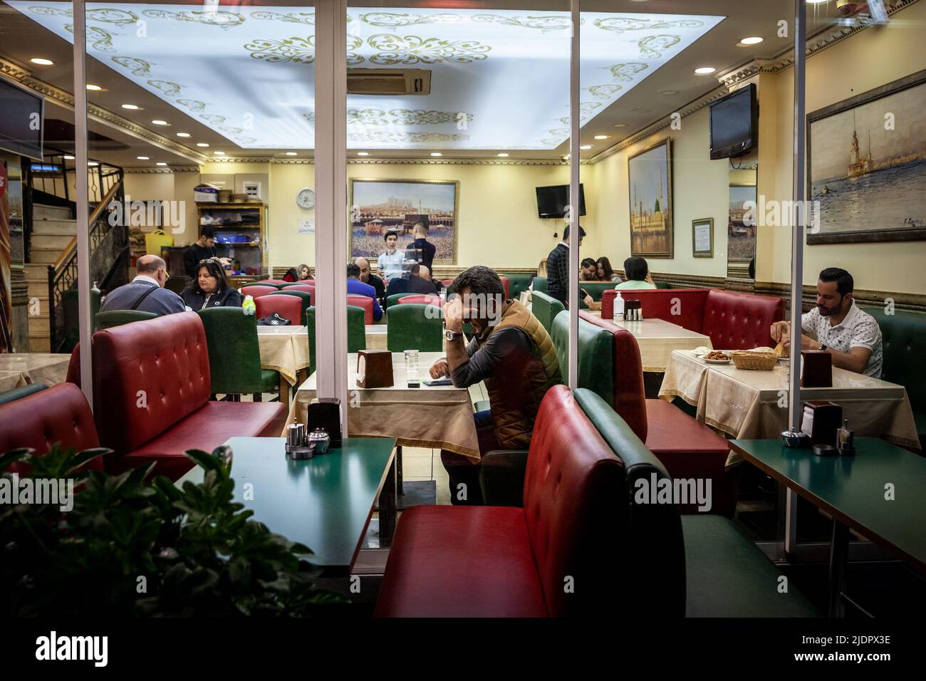 Bild von Männern in einem türkischen Restaurant in istanbul, türkei, einige essen, andere benutzen sein Smartphone-Handy, um nachts im Internet zu surfen. Stockfoto