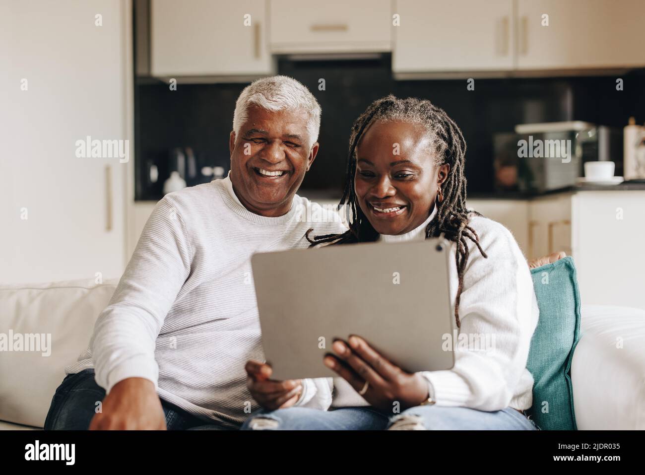 Reifes Paar lächelt fröhlich, während es einen Videoanruf auf einem digitalen Tablet hat. Glückliches Seniorenpaar, das online mit seinen Angehörigen kommuniziert. Reif Stockfoto