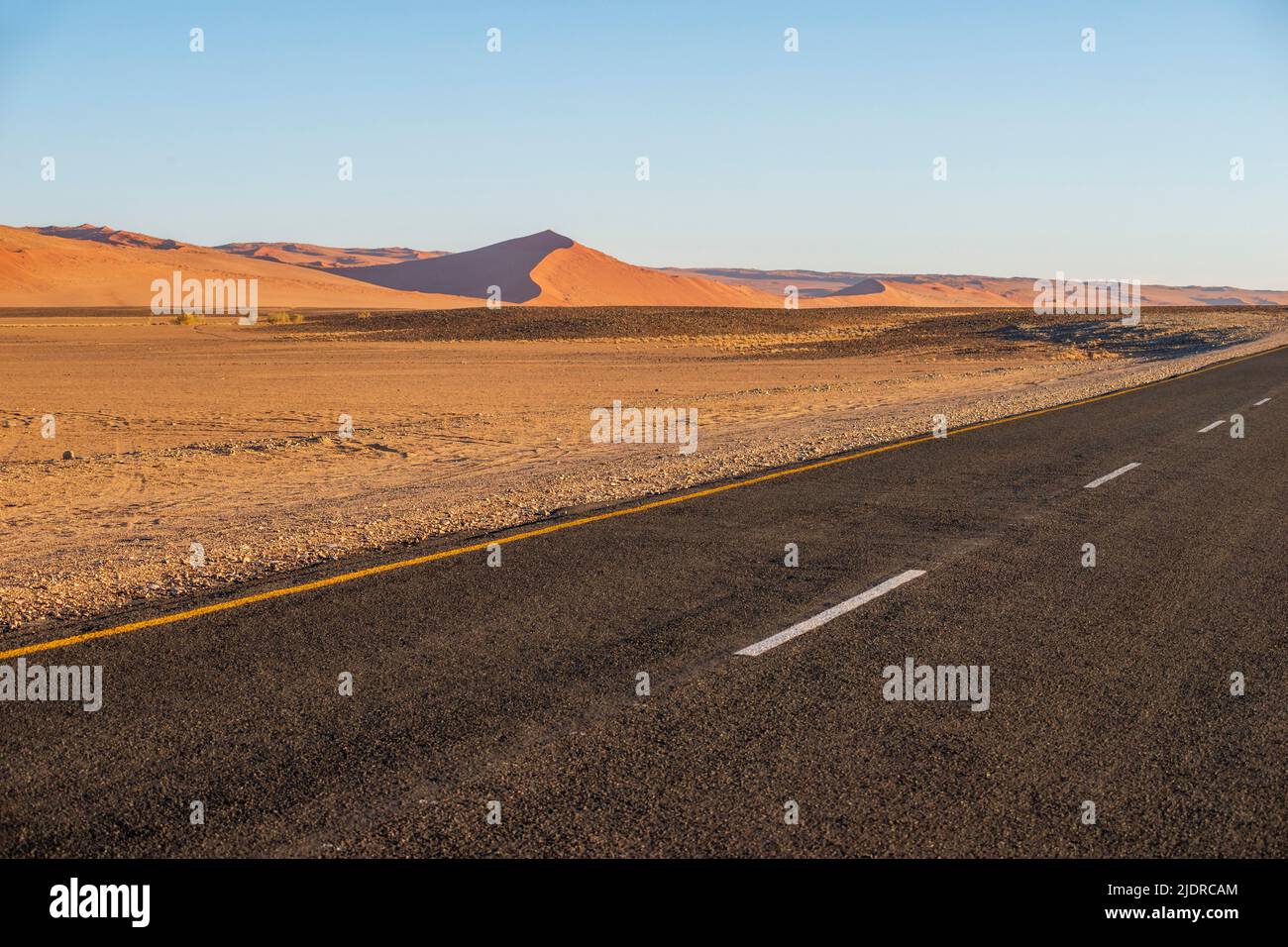 Rote Sanddünen-Landschaft mit Highway-Oberfläche auf Vorgrund in Namibia Stockfoto