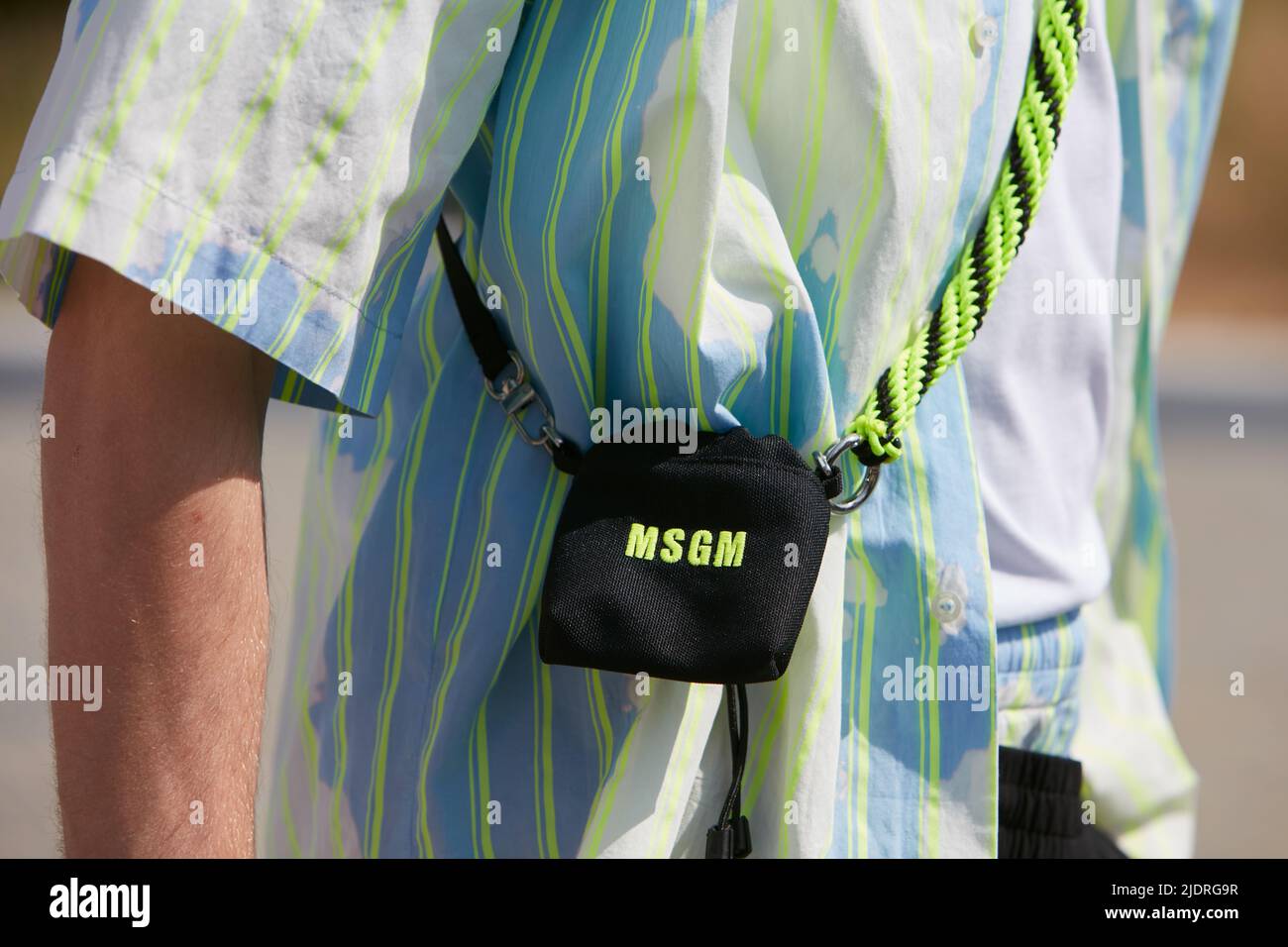 MAILAND, ITALIEN - 18. JUNI 2022: Mann mit fluurescent grün gestreiftem Hemd und kleiner MSGM Tasche vor MSGM Fashion Show, Milan Fashion Week Street Style Stockfoto