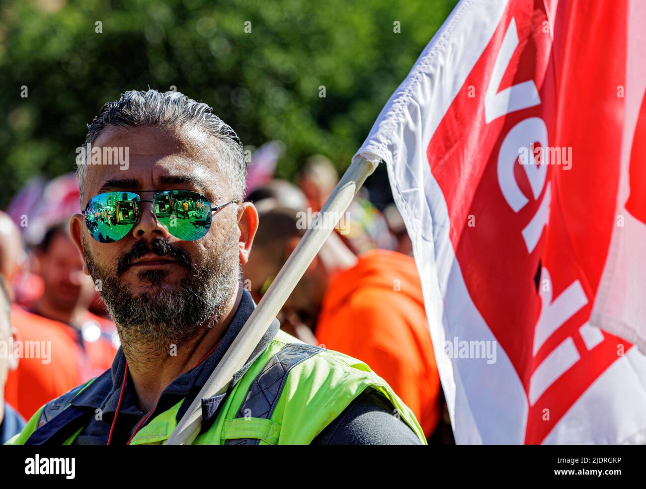 Hamburg, Deutschland. 23.. Juni 2022. Ein Hafenarbeiter demonstriert mit einer Gewerkschaftsflagge in der Hamburger HafenCity. Die Gewerkschaft Verdi ruft Hafenarbeiter zu einem 24-stündigen Warnstreik auf. Quelle: Axel Heimken/dpa/Alamy Live News Stockfoto