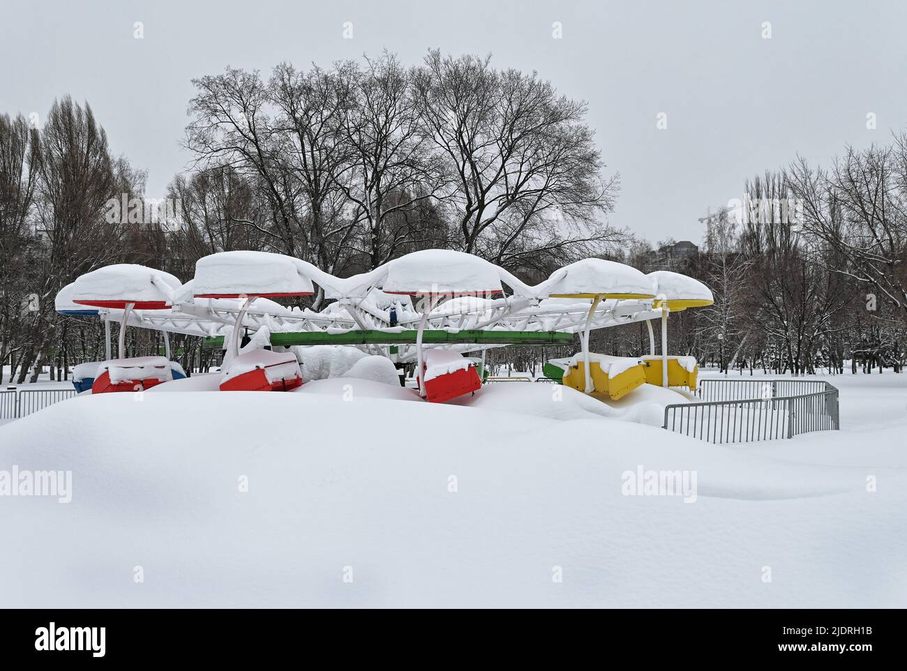 Altes schneebedecktes Karussell im verschneiten Stadtpark am düsteren Wintertag Stockfoto