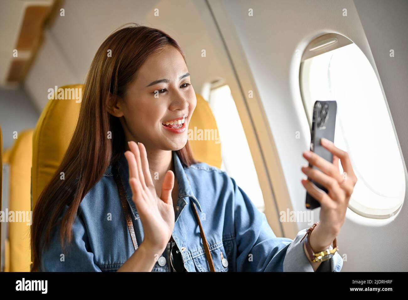 Die wunderschöne, tausendjährige asiatische Reisebloggerin nahm sich während des Fluges in ihre Reisestadt mit einem Smartphone auf. Reiseblogger im Flugzeug Stockfoto