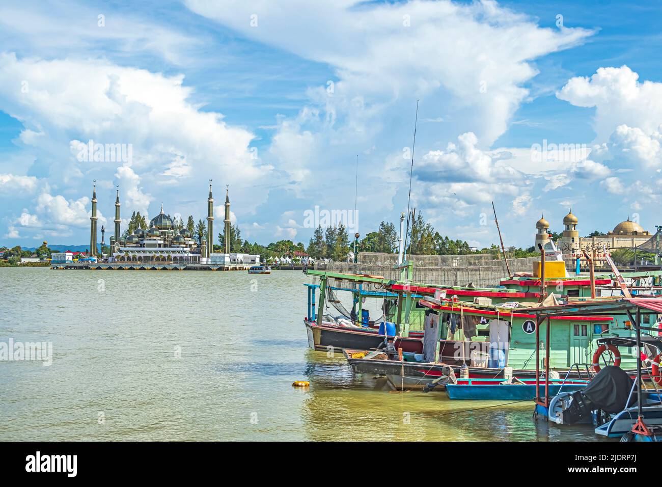Reihe von Fischerbooten auf Pulau Duyong Island in der Mündung des Flusses Sungai Terengganu mit Kristallmoschee oder Masjid Kristal im Hintergrund. Stockfoto