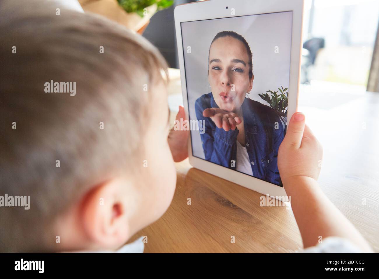 Mutter gibt ihrem kleinen Sohn einen Geburtstagsluftkuss auf dem Tablet-Computer Stockfoto