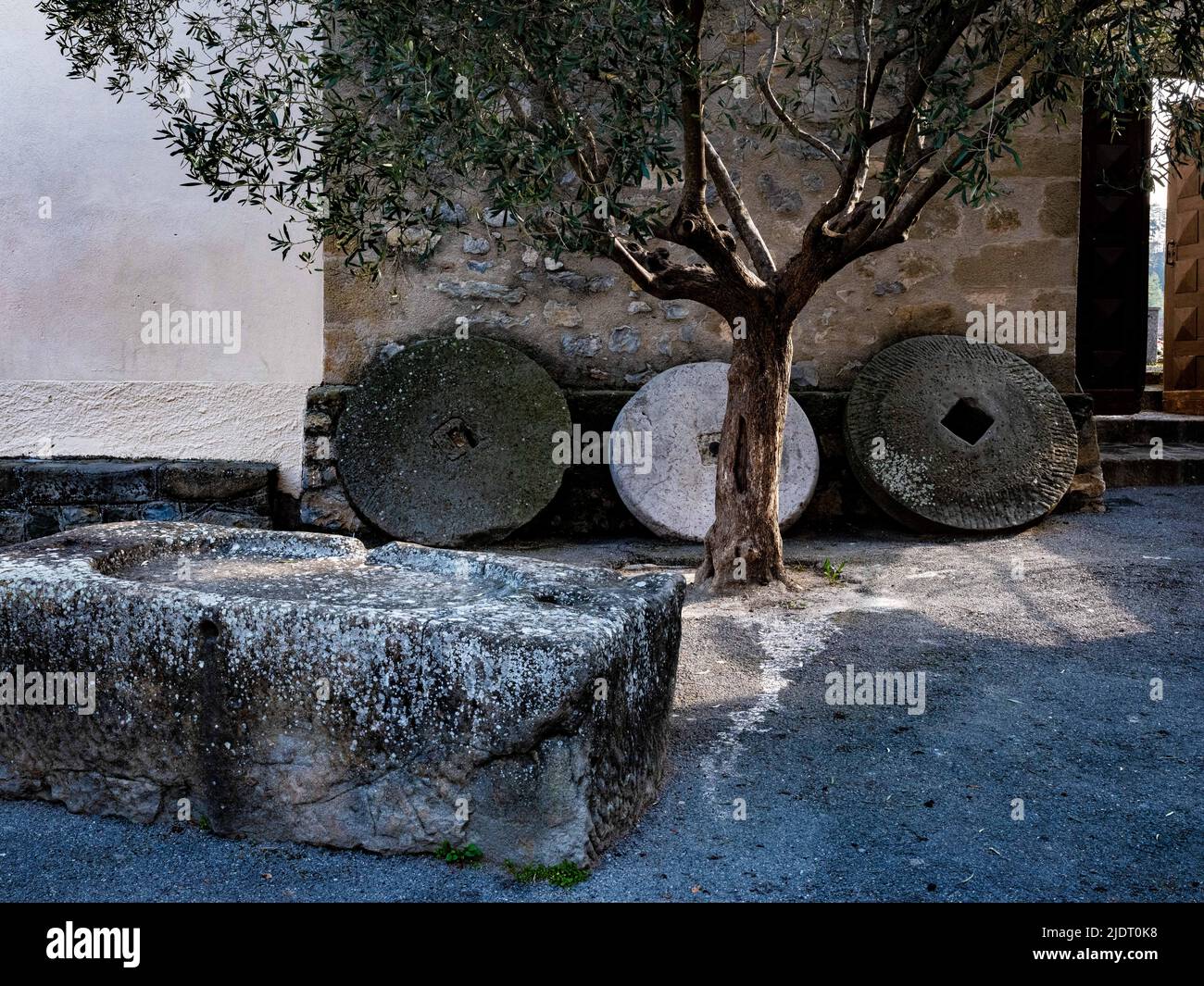Drei Mühlsteine säumen die Wand eines Gebäudes im Dorf Villars-sur-Var in Provençal in den Seealpen im Südosten Frankreichs Stockfoto