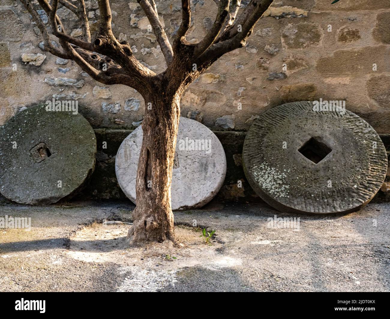 Drei Mühlsteine säumen die Wand eines Gebäudes im Dorf Villars-sur-Var in Provençal in den Seealpen im Südosten Frankreichs Stockfoto