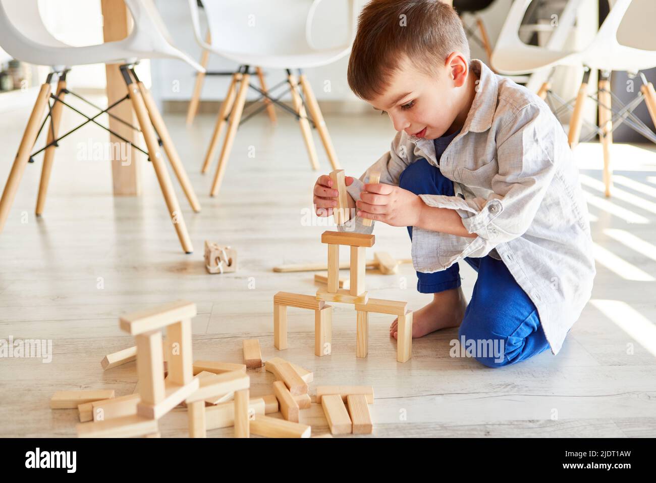 Der kleine Junge baut einen Turm aus Holzblöcken für die Entwicklung von Gleichgewicht und Motorik Stockfoto