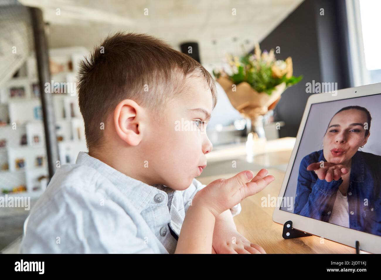 Das Kind macht per Tablet-Computer einen Video-Chat mit seiner Mutter und gibt ihr einen Luftkuss Stockfoto