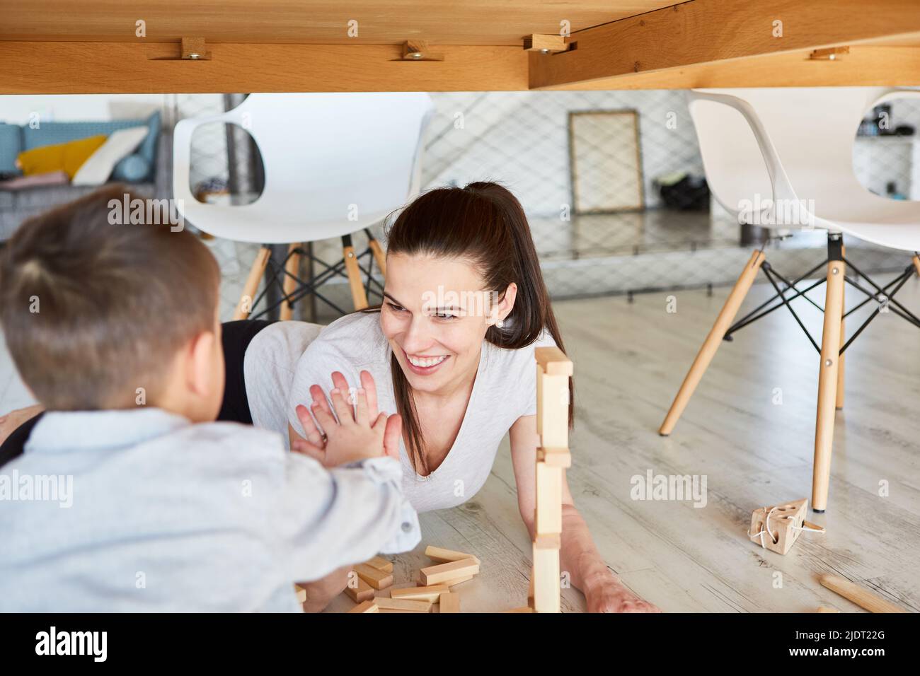 Mama und Sohn spielen im Wohnzimmer mit Bausteinen zusammen und geben hohe fünf Stockfoto