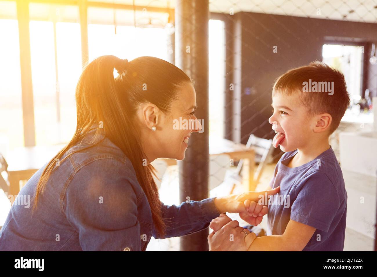 Freche Kind, das seine Mutter zu Hause mit der Zunge anstreckt Stockfoto