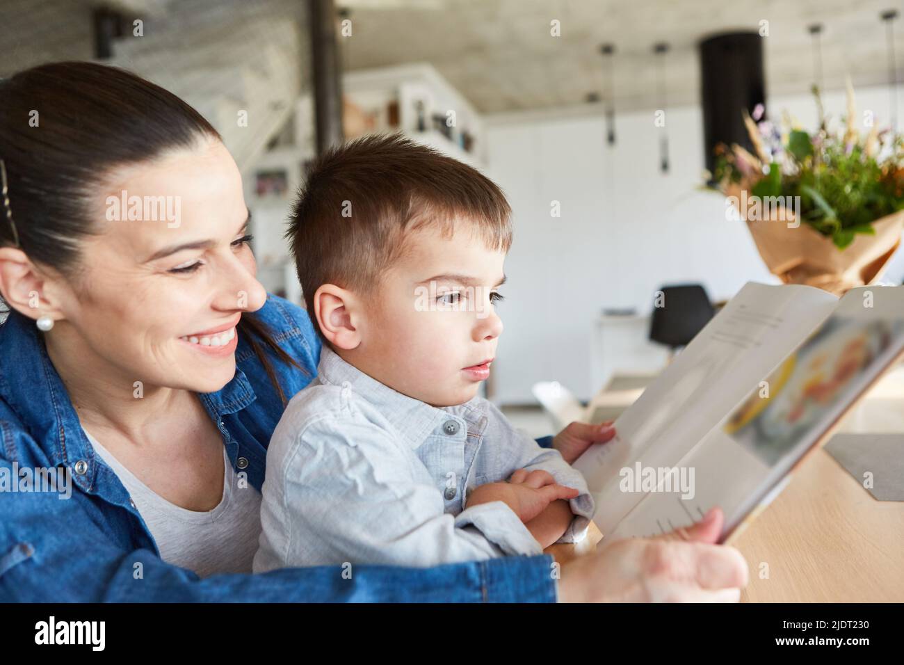 Mutter und Sohn schauen sich zu Hause gemeinsam ein Bilderbuch oder ein Storybook an Stockfoto