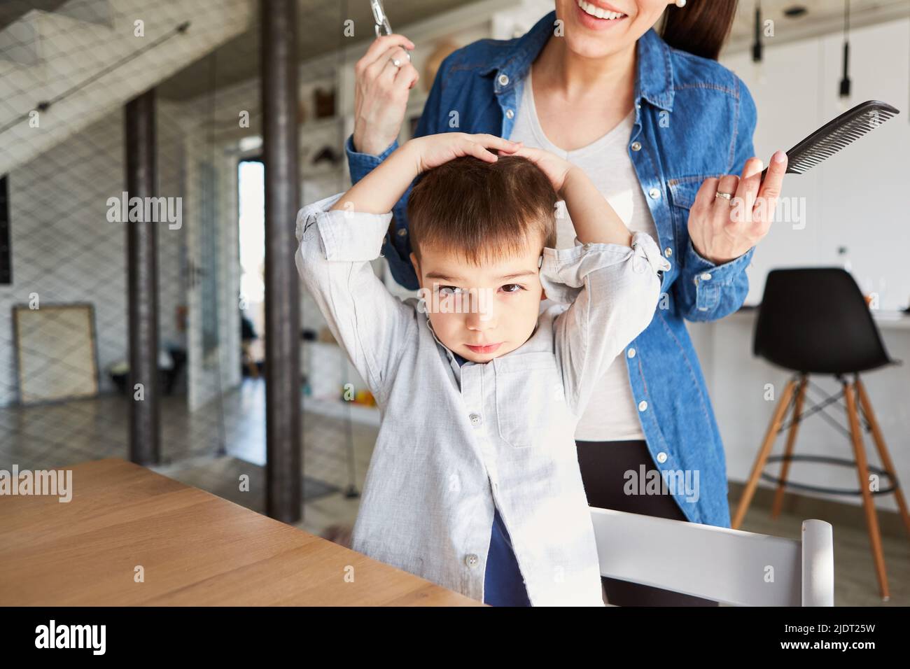Boy steuert seine Frisur, wenn er beim Friseur oder bei seiner Mutter die Haare schneidet Stockfoto
