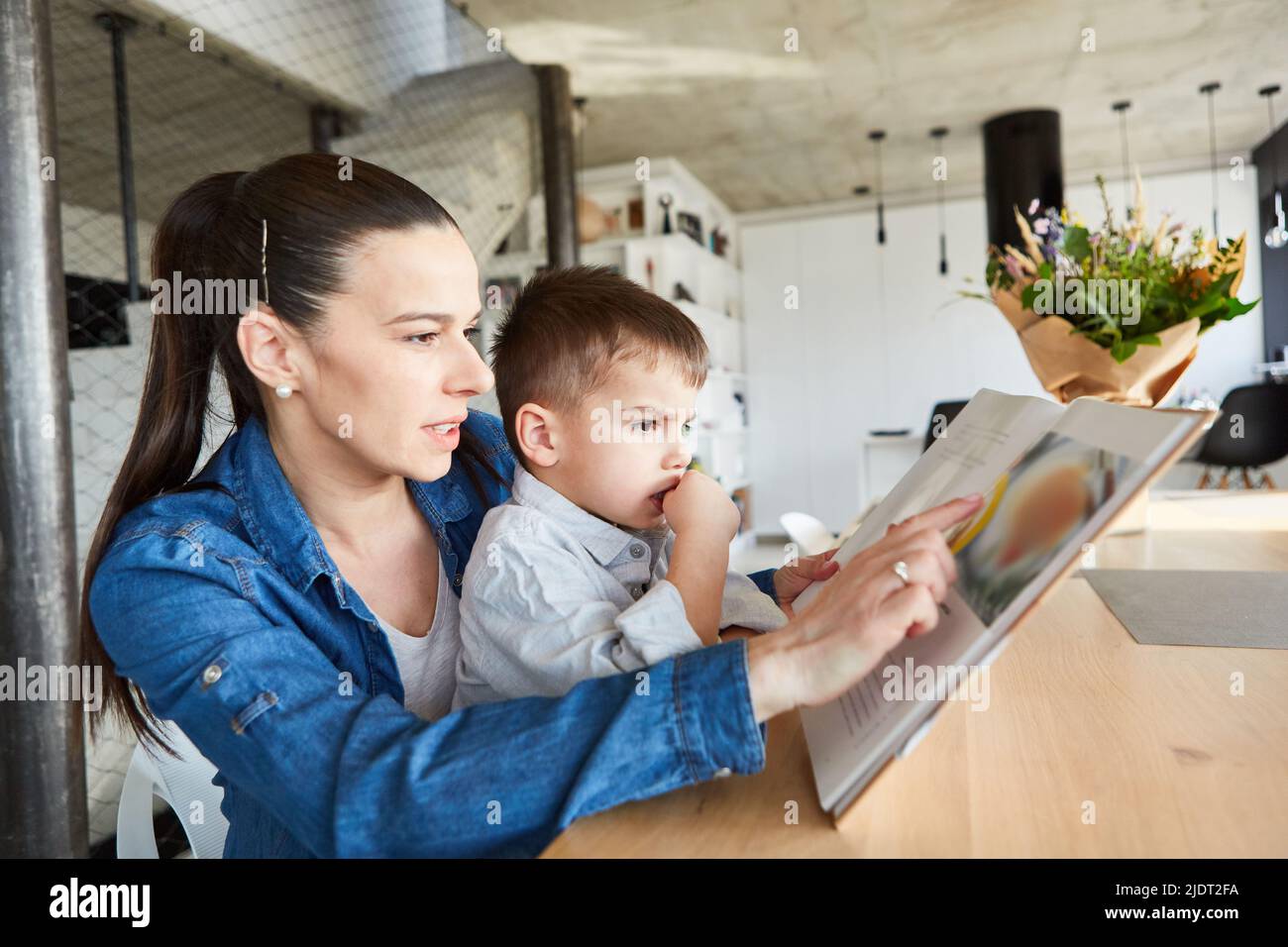 Mutter liest ihrem Sohn eine Geschichte aus einem Märchenbuch zu Hause im Wohnzimmer vor Stockfoto