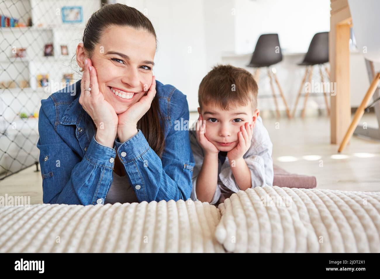 Mutter und Sohn liegen zu Hause im Wohnzimmer Seite an Seite und legen sich auf die Hände Stockfoto